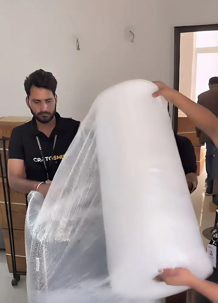CratoShift mover wrapping a sofa in bubble wrap before loading